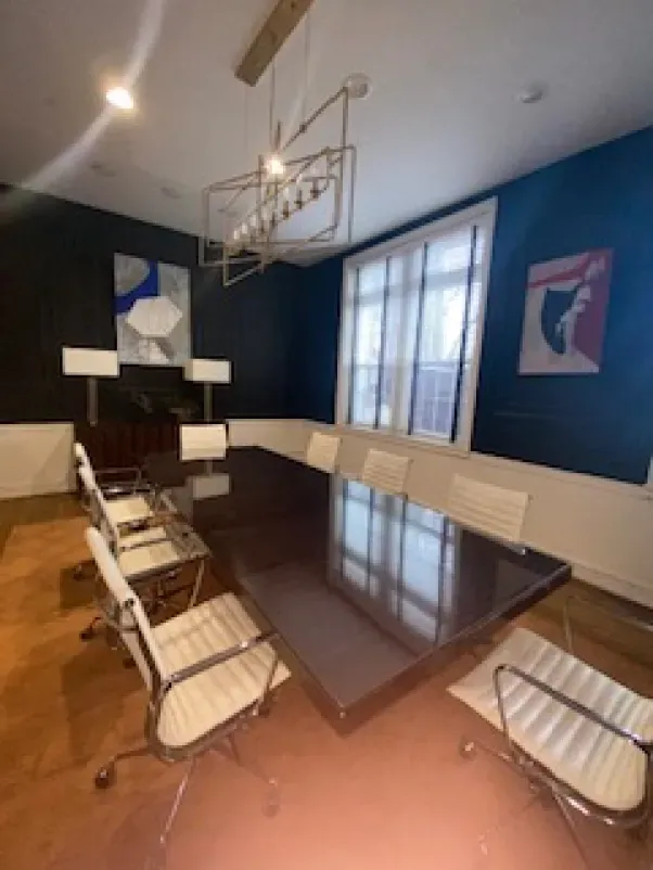 A conference room with a long table and white chairs