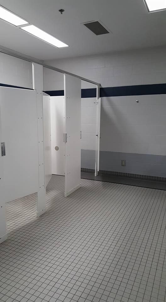 A bathroom with a tiled floor and white stalls.