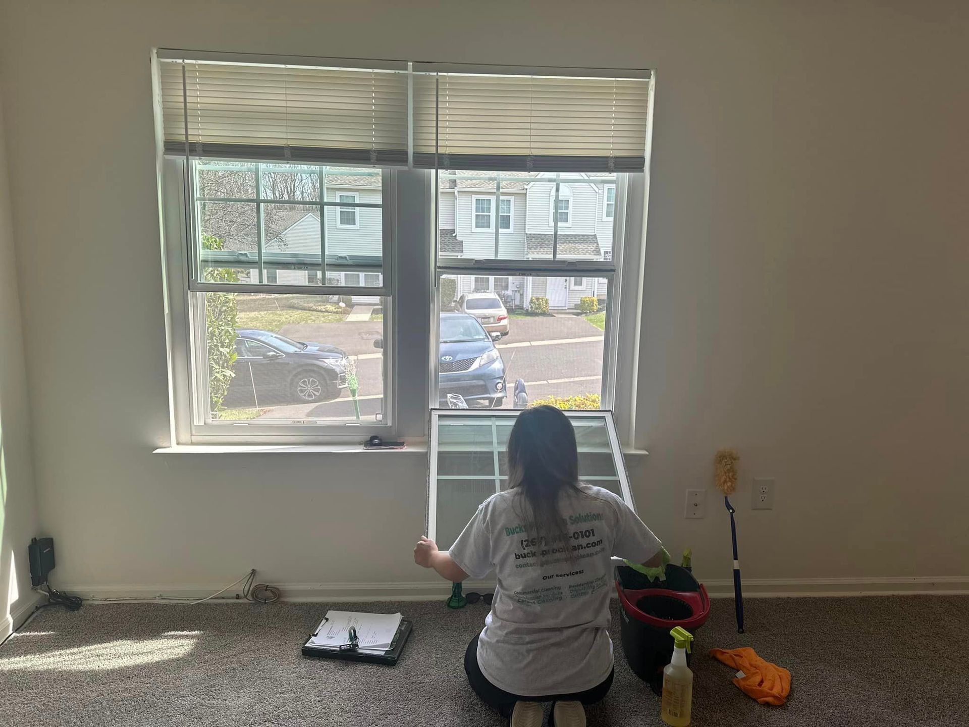 A woman is cleaning a window in an empty room.