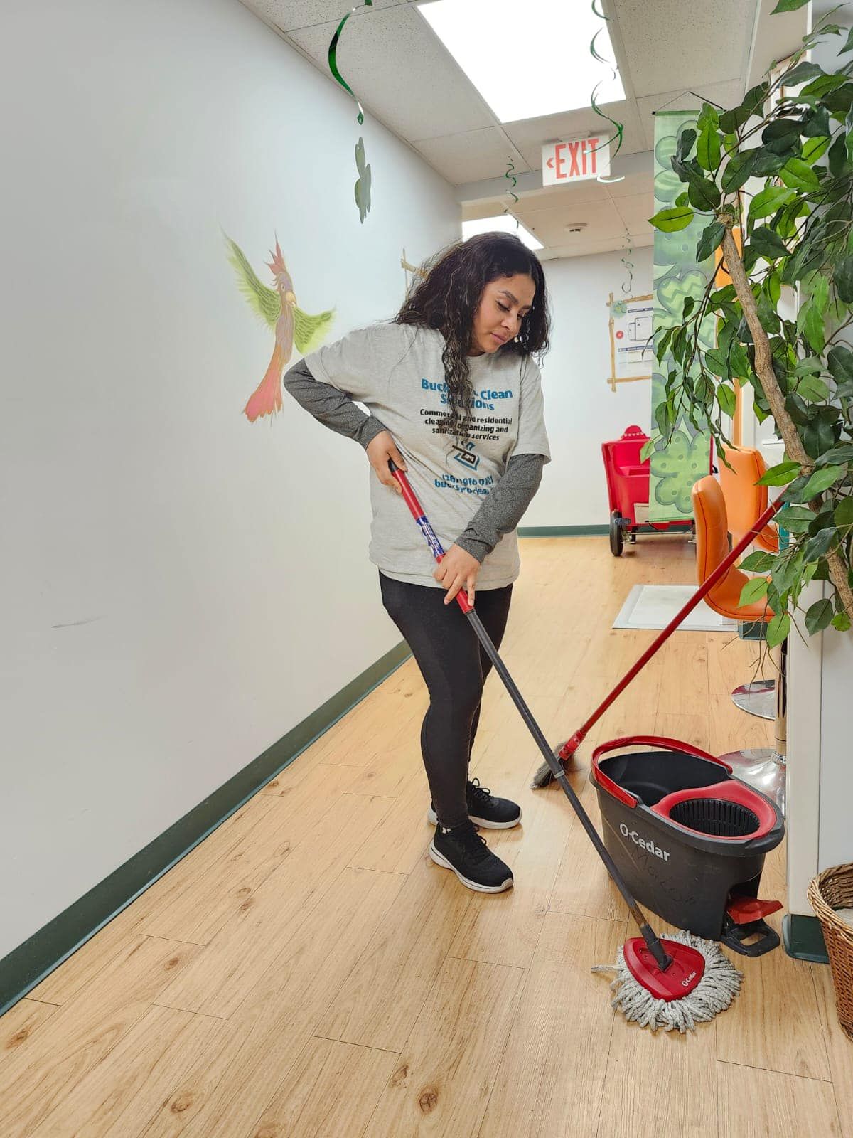 A woman is cleaning the floor with a mop and bucket.