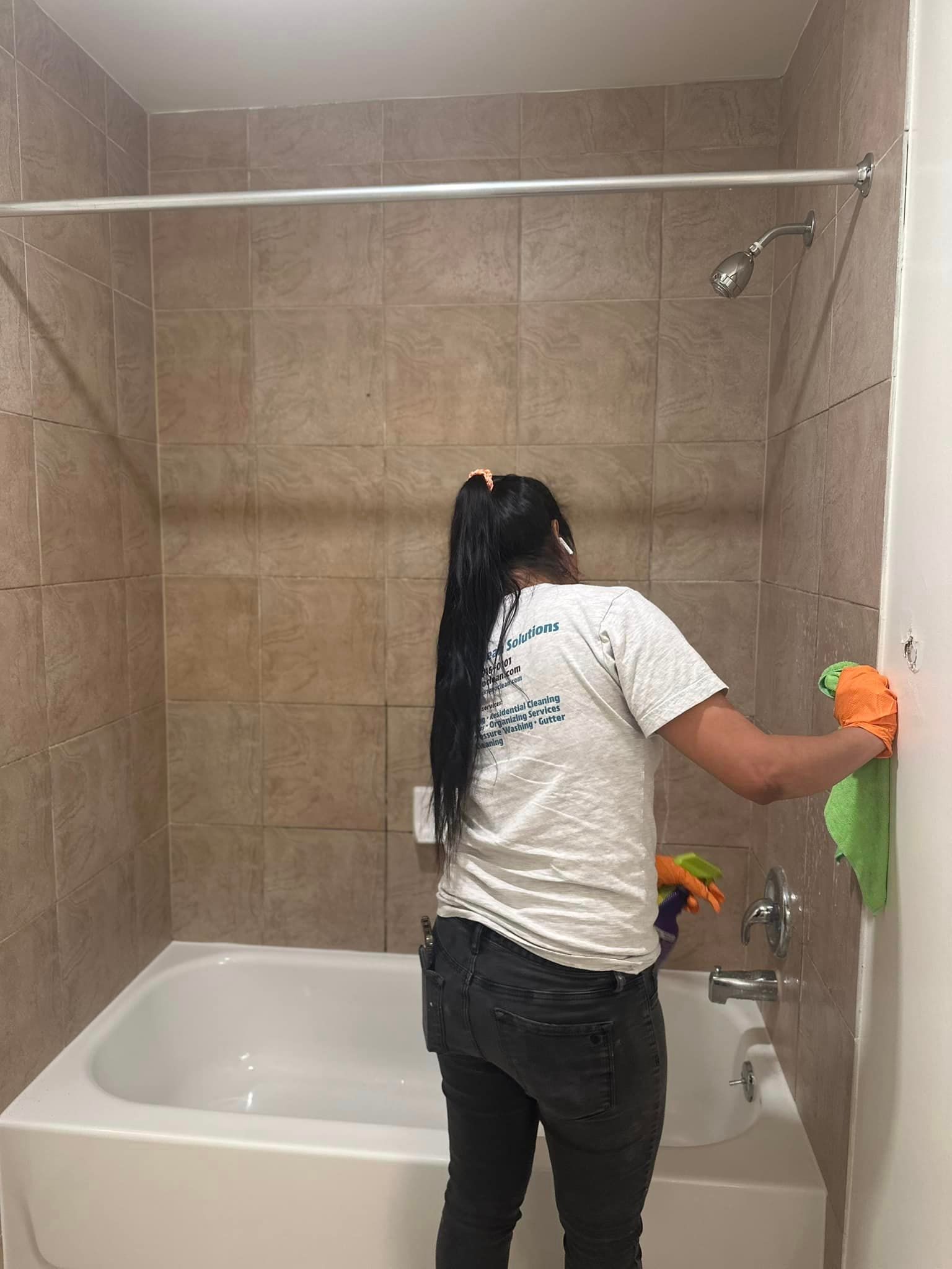 A woman is cleaning a bathroom with a towel.