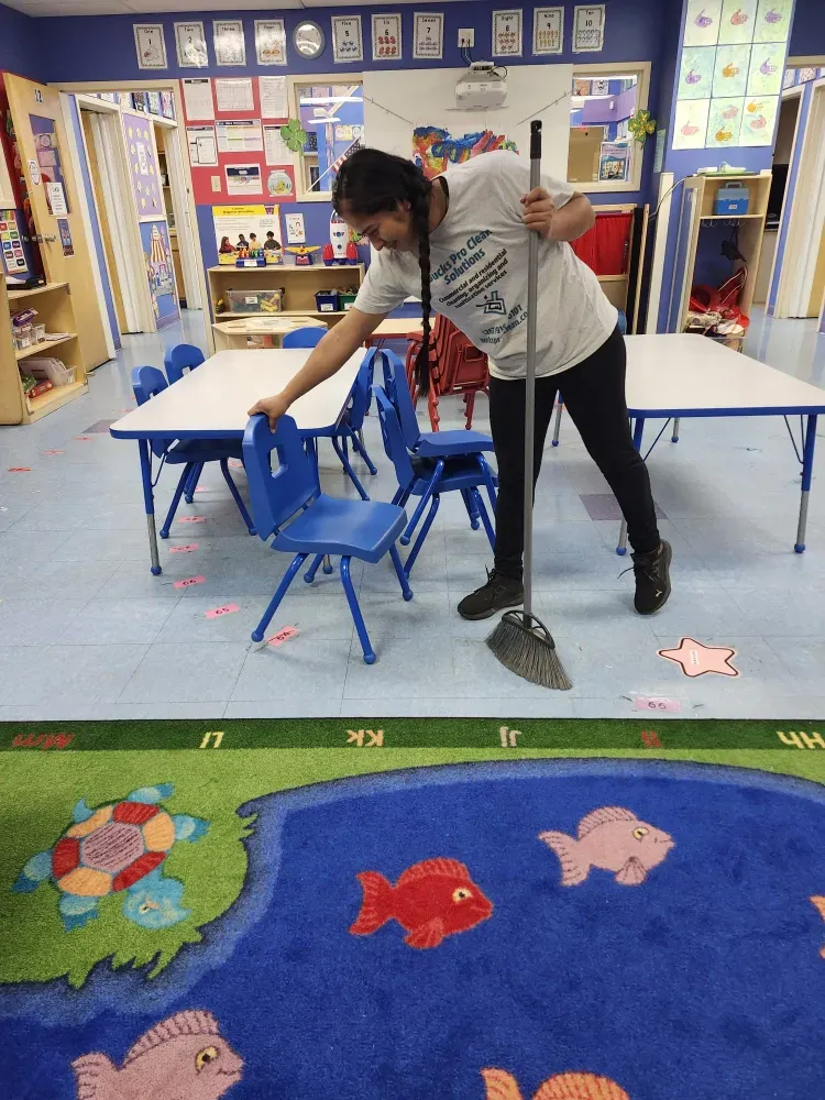 A man is cleaning a classroom with a mop