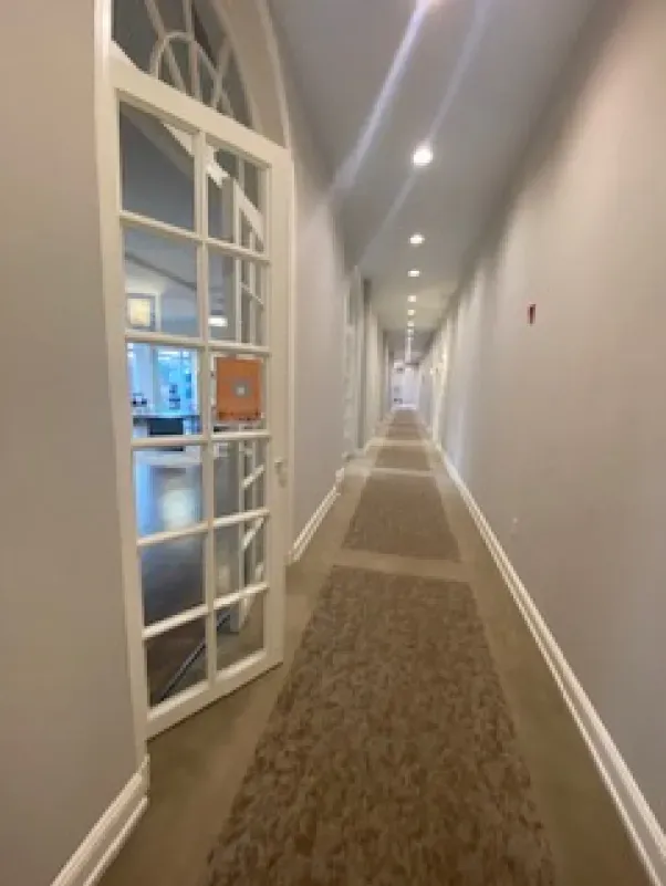 A long hallway with a glass door leading to a room.