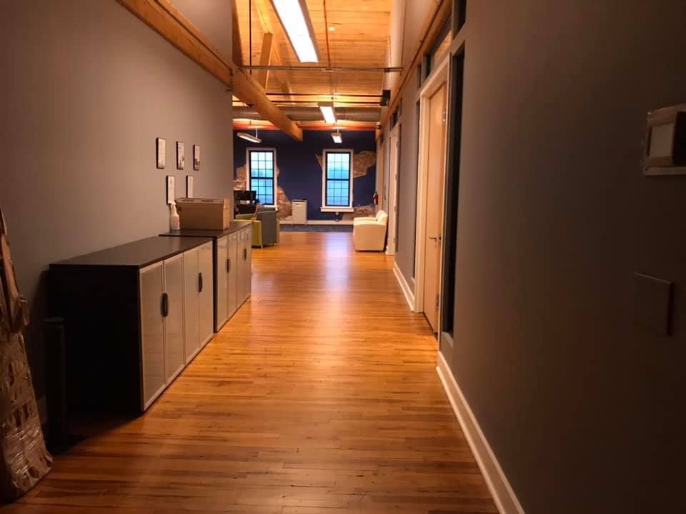 A long hallway with hardwood floors and a few cabinets