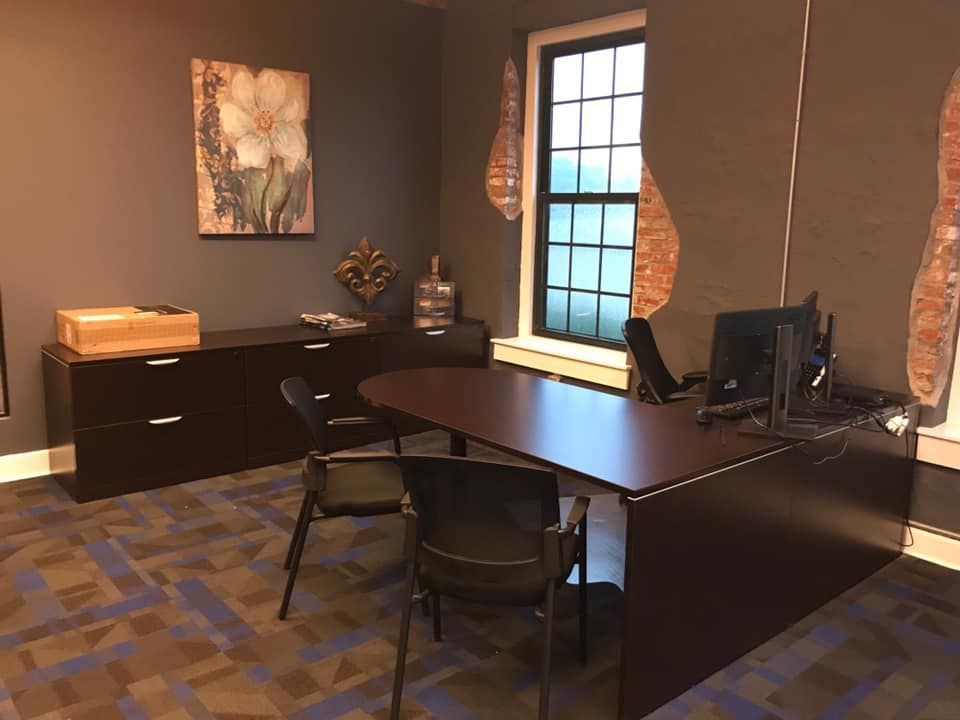 A small office with a desk and chairs and a window.
