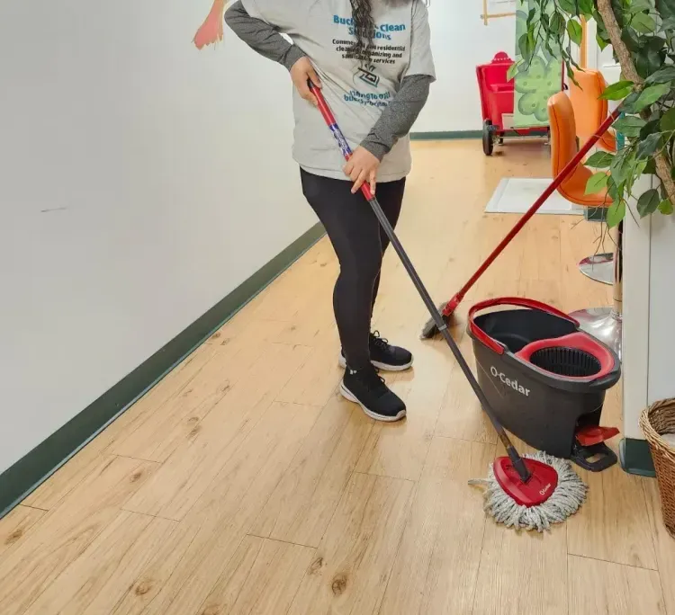 A woman is cleaning the floor with a mop and bucket