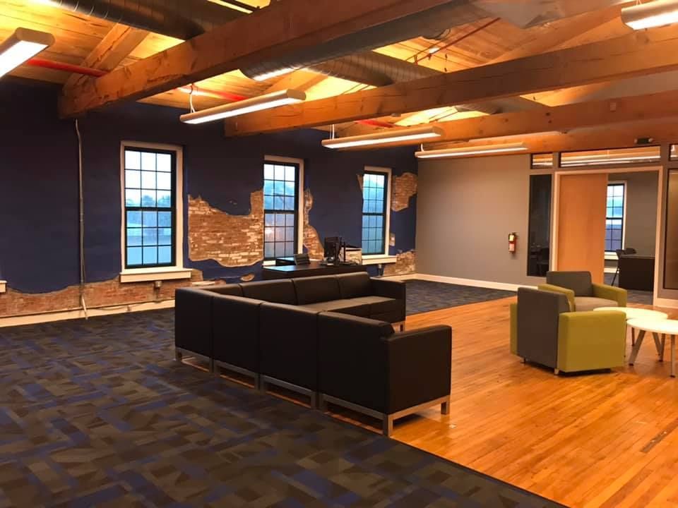 A living room with a couch , chairs , tables and windows.