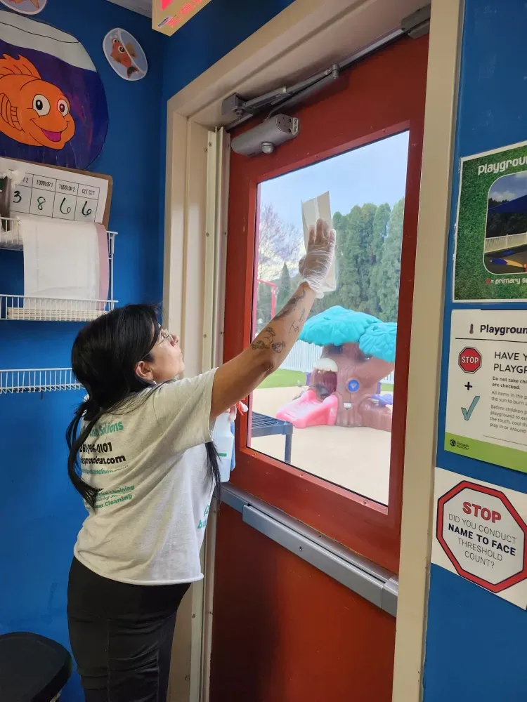 A woman is cleaning a red door with a cloth.