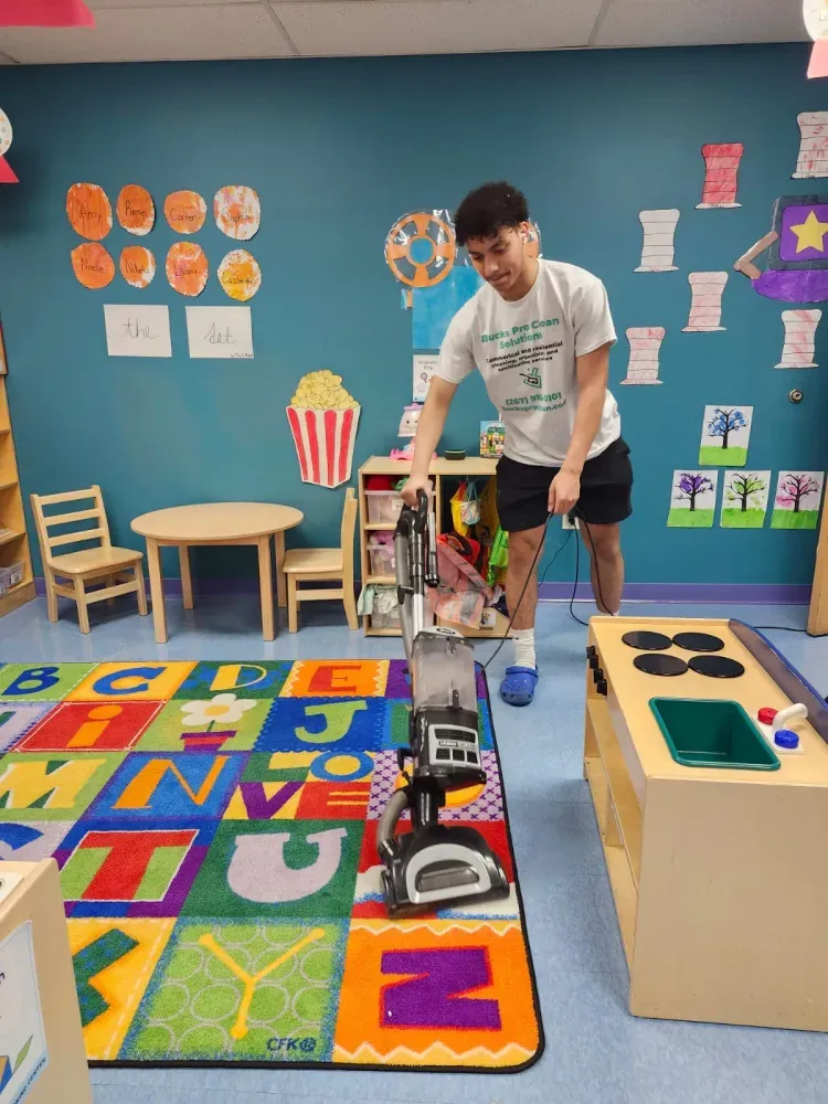 A man is using a vacuum cleaner in a play room