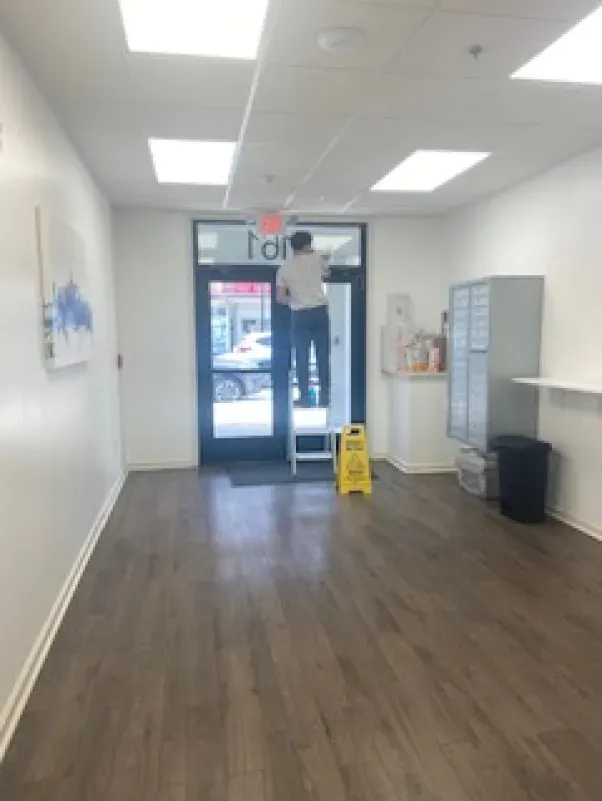 A man is standing on a ladder in an empty room.
