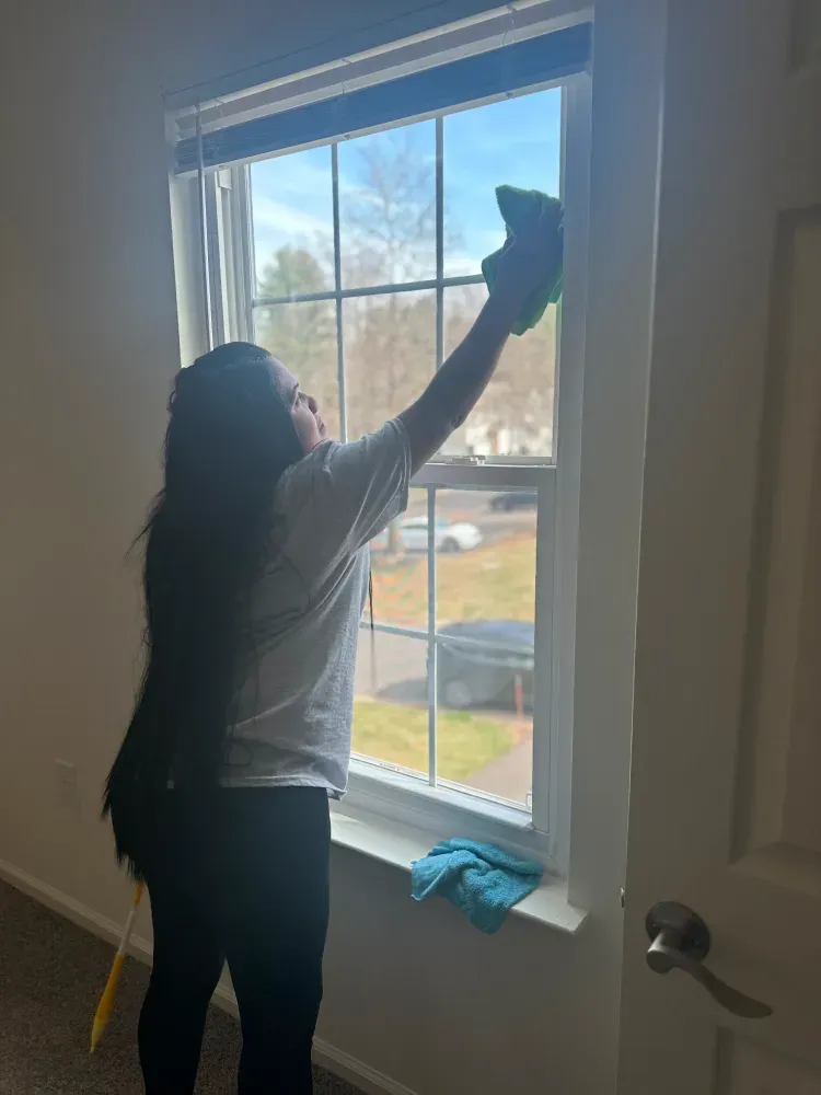 A woman is cleaning a window with a cloth.