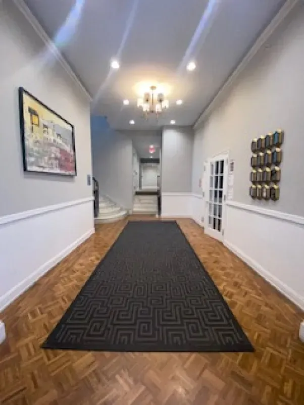 A long hallway with a rug on the floor and a picture on the wall.