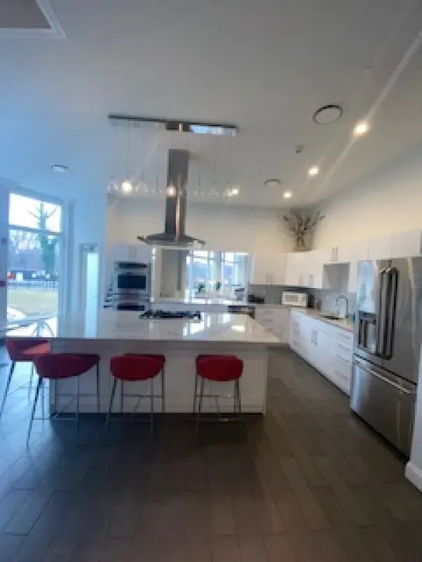 A kitchen with white cabinets and red stools