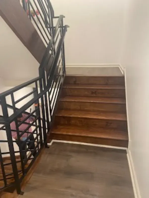A wooden staircase with a metal railing in a house.