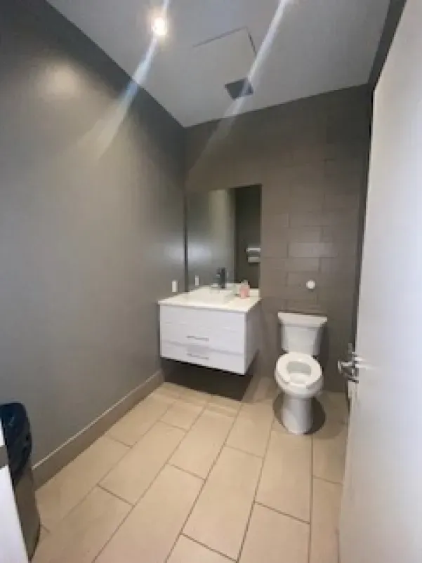A bathroom with a toilet , sink and mirror.