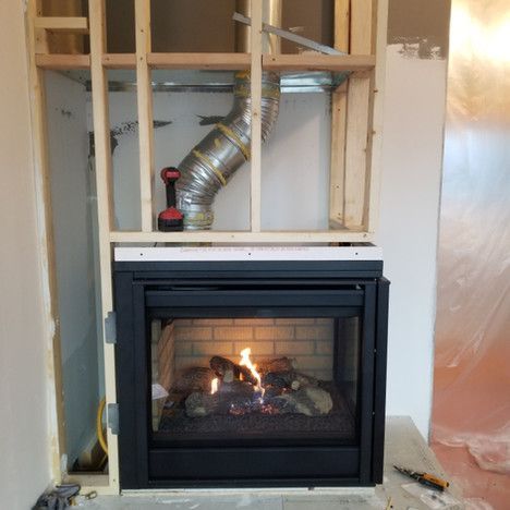 A fireplace is being built in a room with a hose coming out of it.