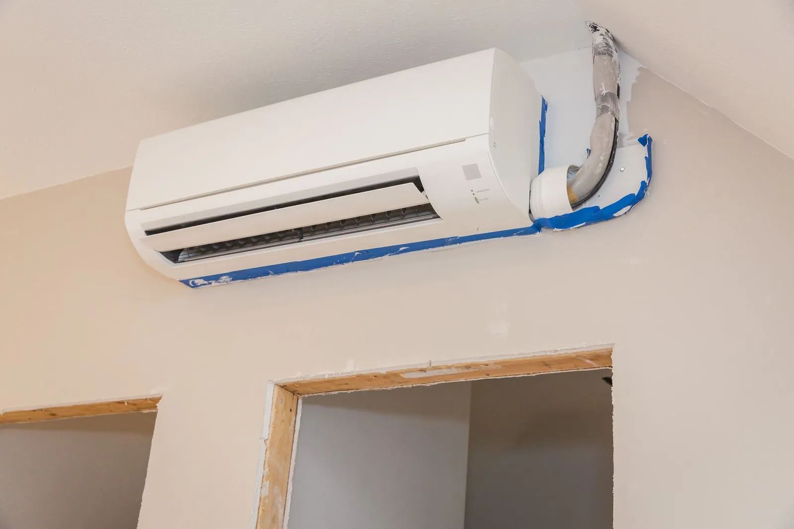 A white air conditioner is hanging from the ceiling in a room.