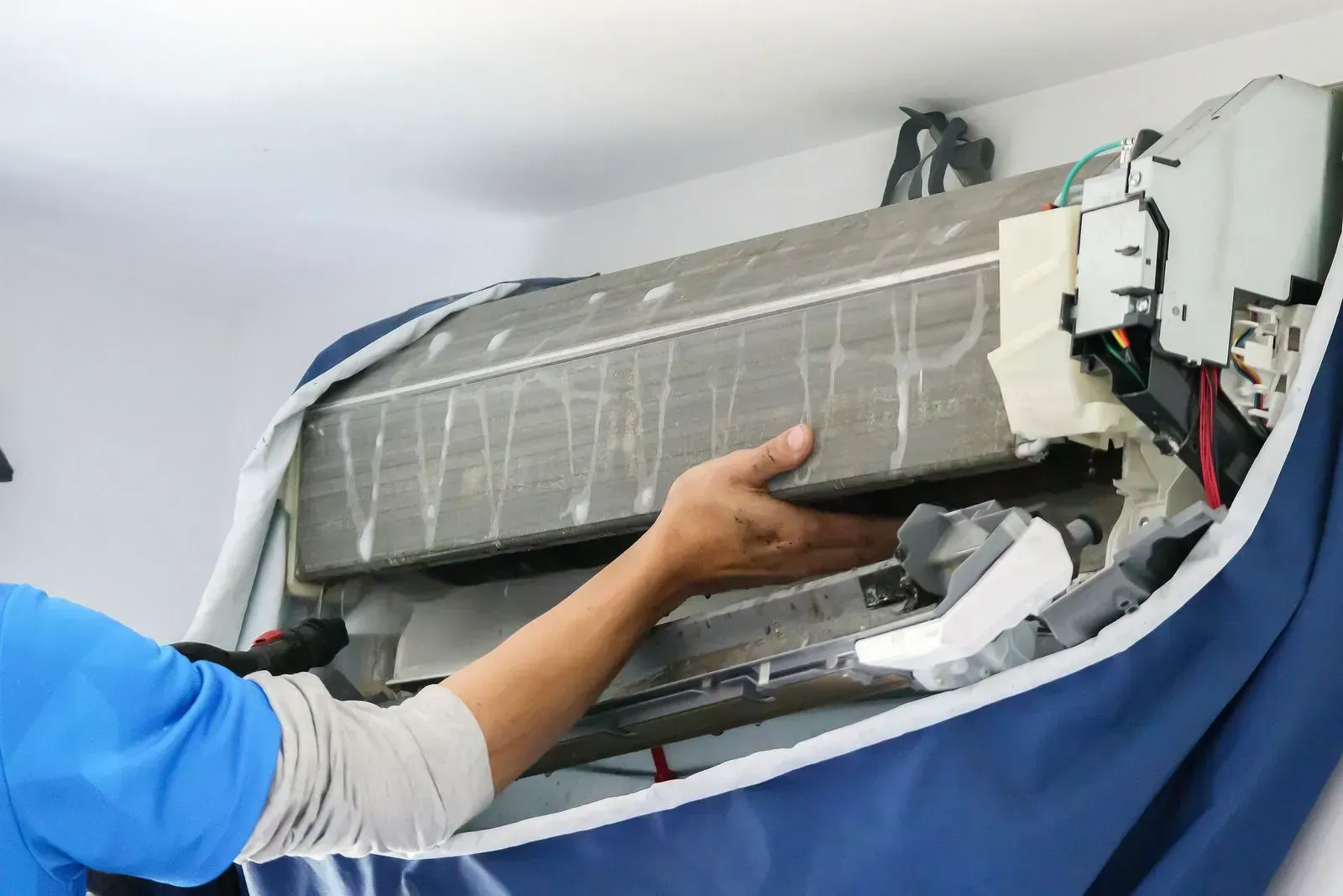 A man is working on an air conditioner in a room.