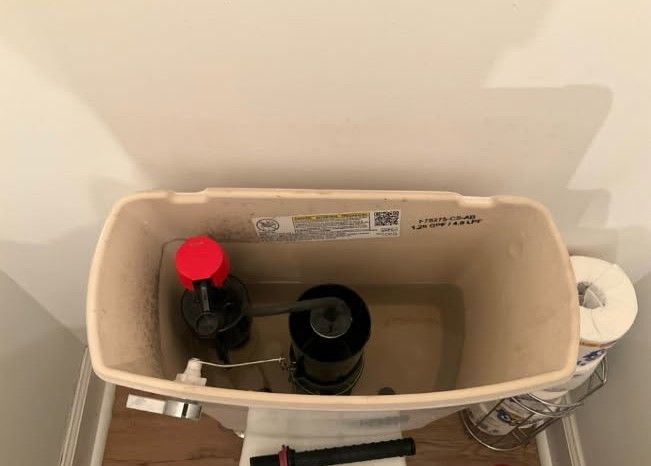 Gas water heater installation in a room with exposed studs and a window.