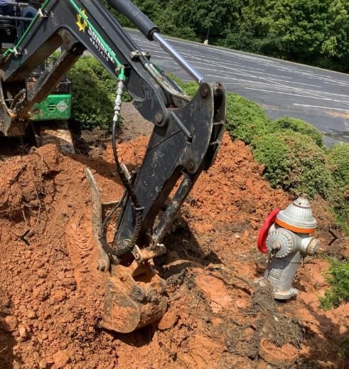 A fire hydrant is sitting in the dirt next to a bulldozer.