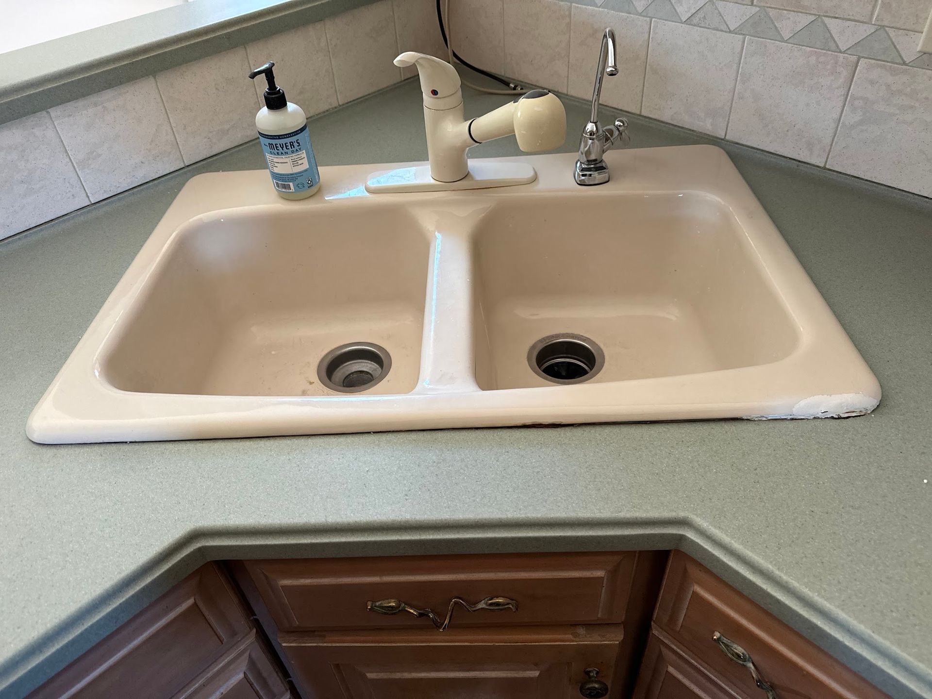 A kitchen sink with a soap dispenser on top of it.