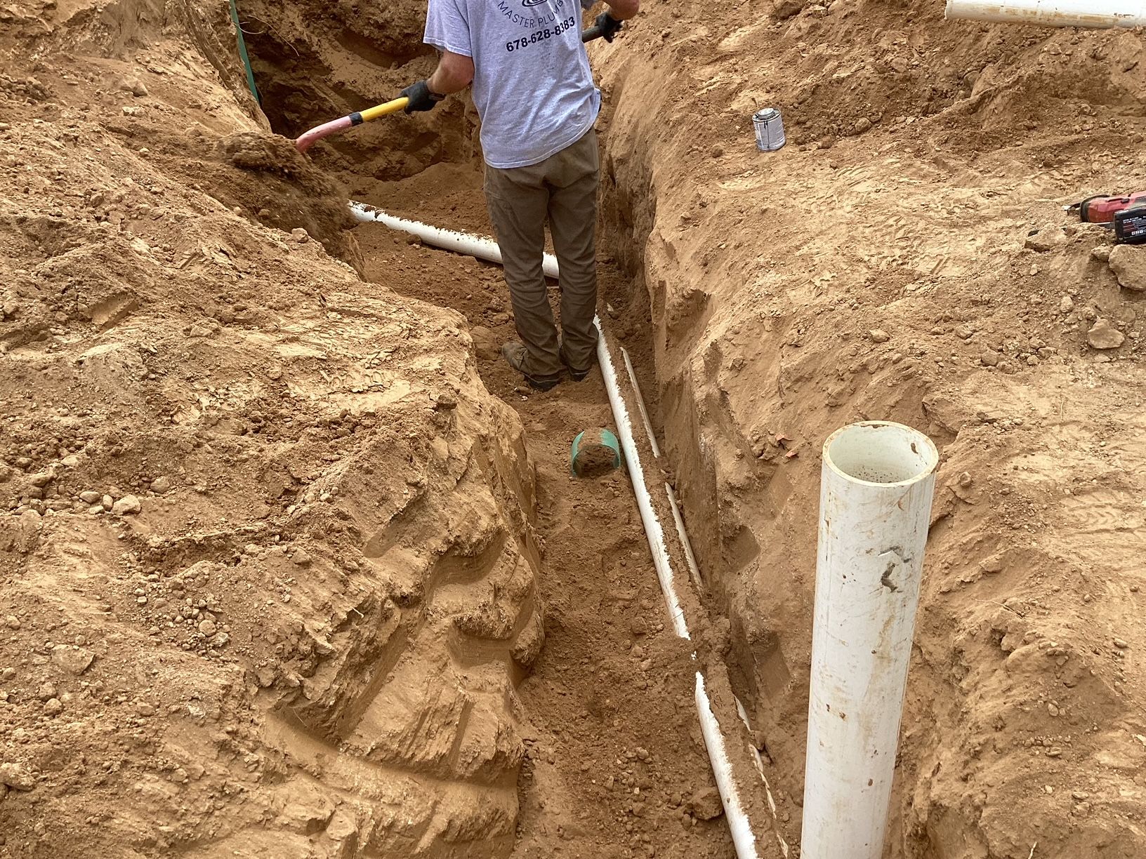 A man is digging a hole in the dirt with a shovel.