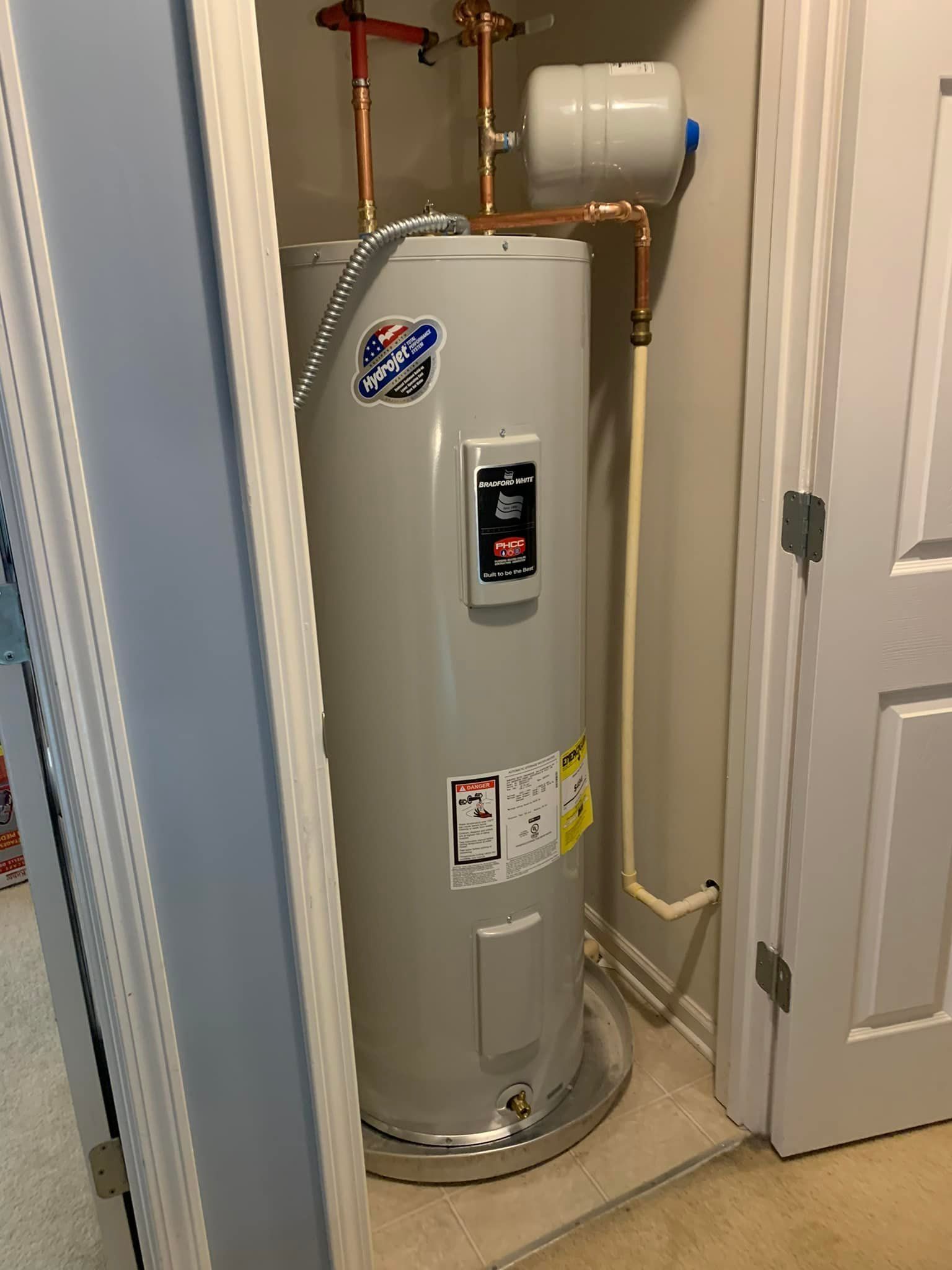 A water heater is sitting in a closet next to a door.