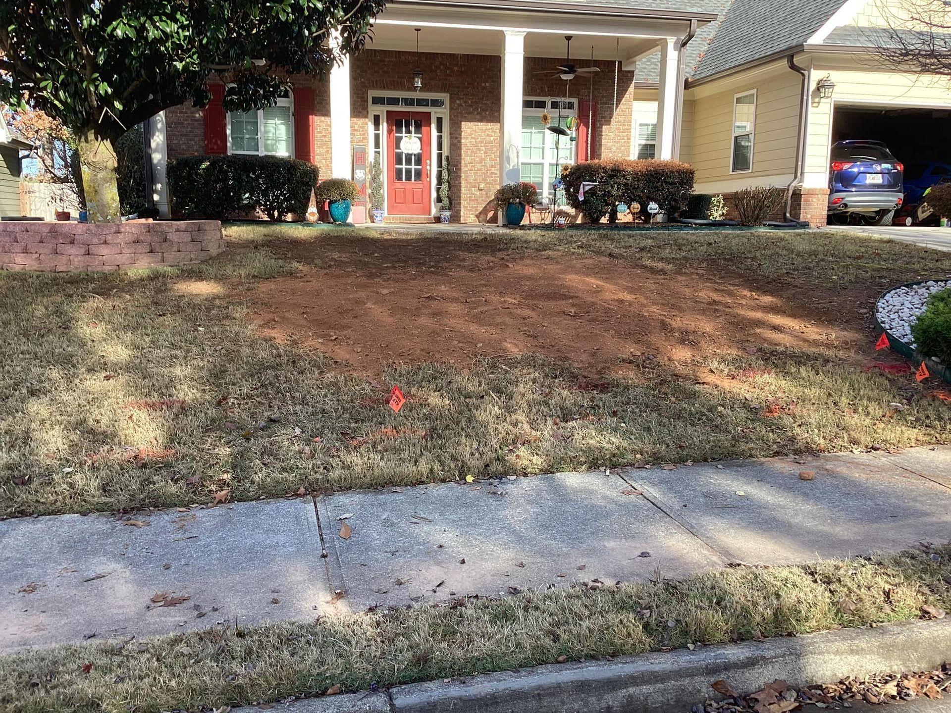 A lawn with a lot of dirt in front of a house.