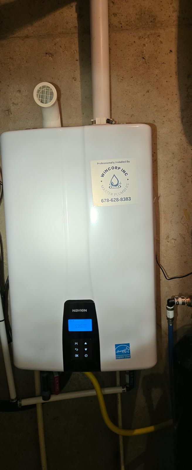 White tank with a blue display screen mounted on a concrete wall.