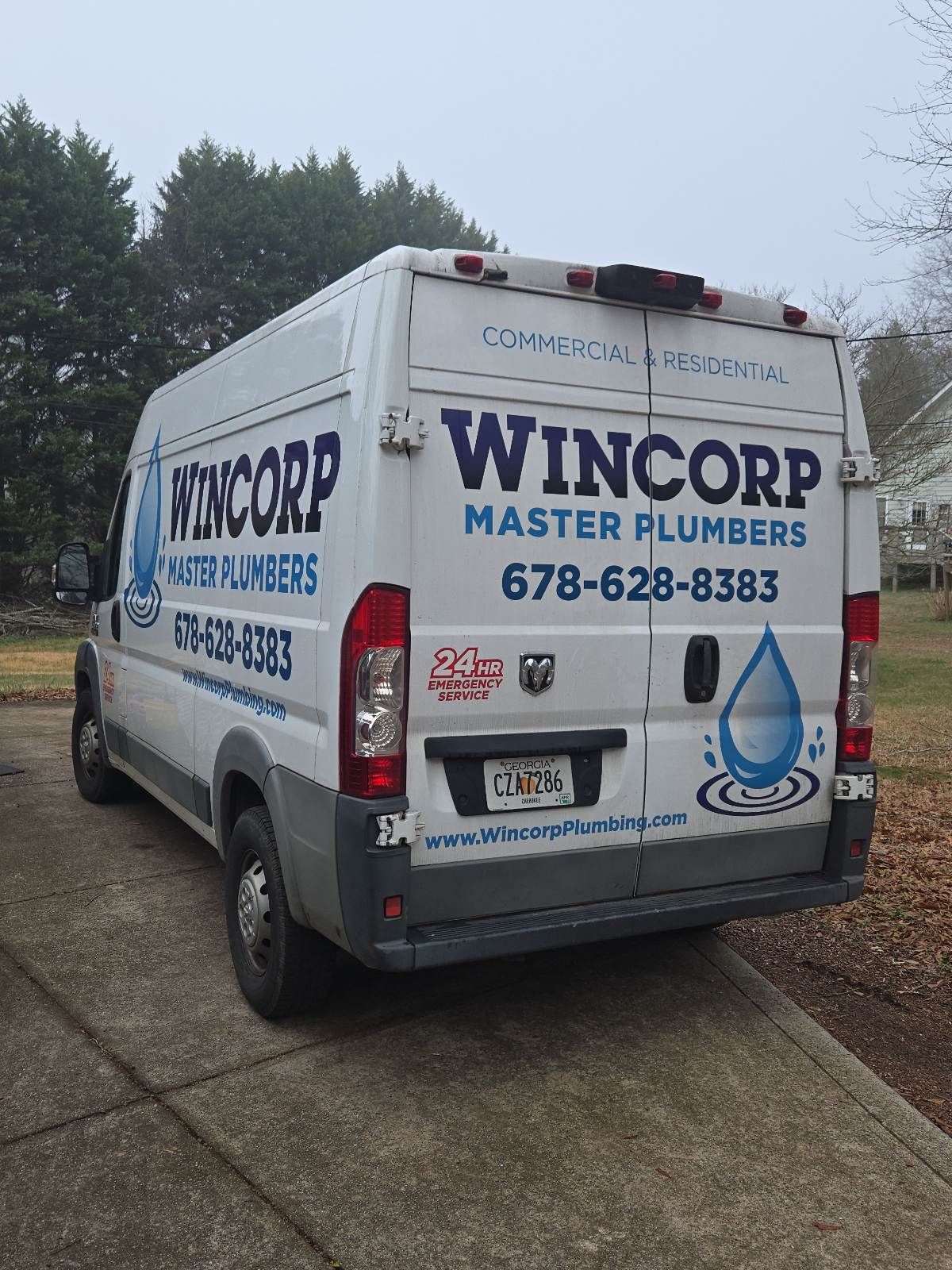 White Wincorp plumbing van parked on a driveway, with business name and phone number visible.