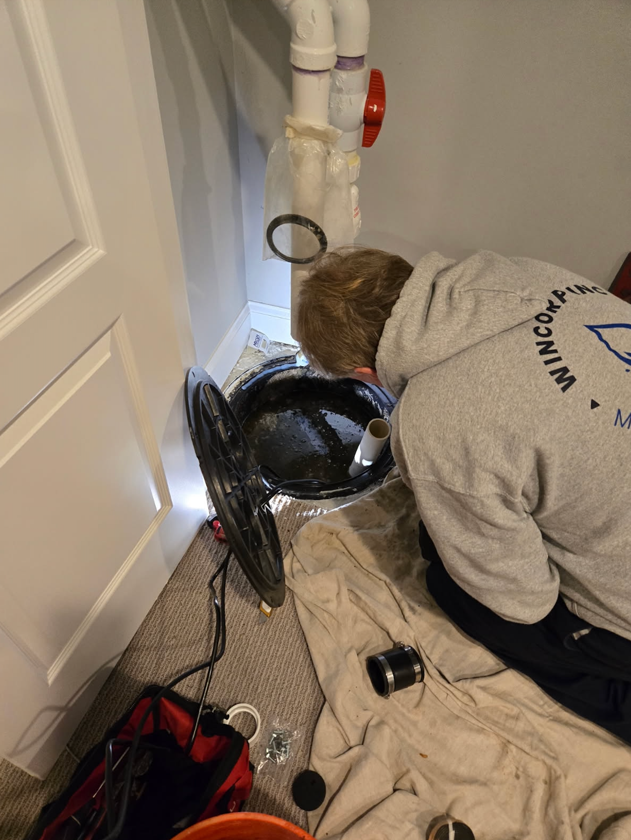 A man is working on a washing machine in a laundry room.