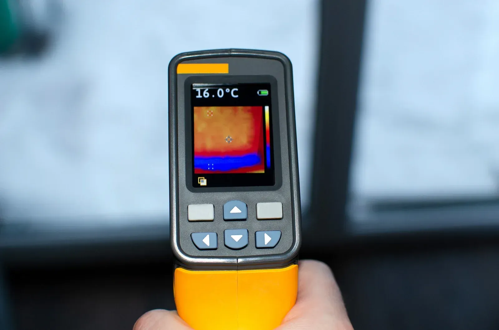 A person is holding a thermal camera in their hand.