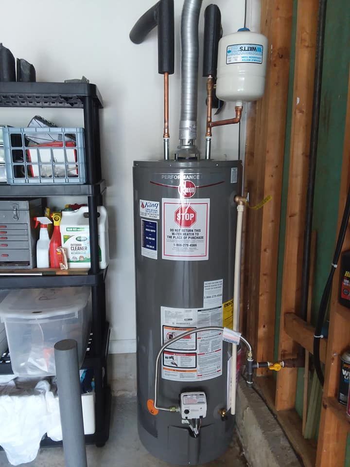A water heater is sitting in a garage next to a shelf