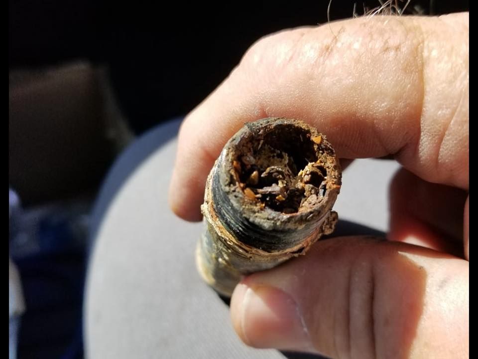 A person is holding a piece of rusty metal in their hand.
