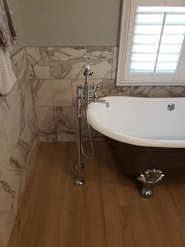 A bathroom with a bathtub and a window with shutters.