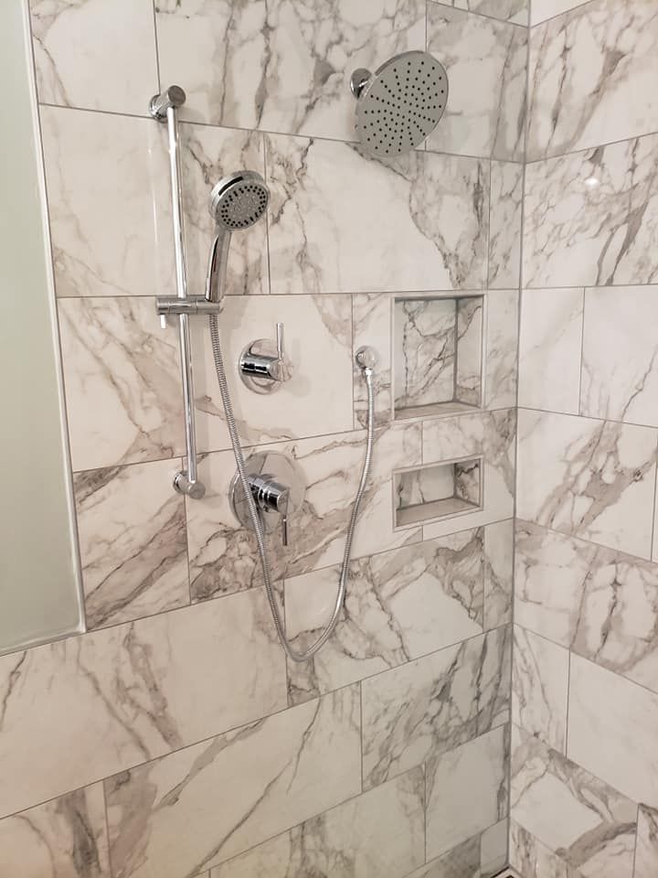 A bathroom with marble tiles and a shower head.