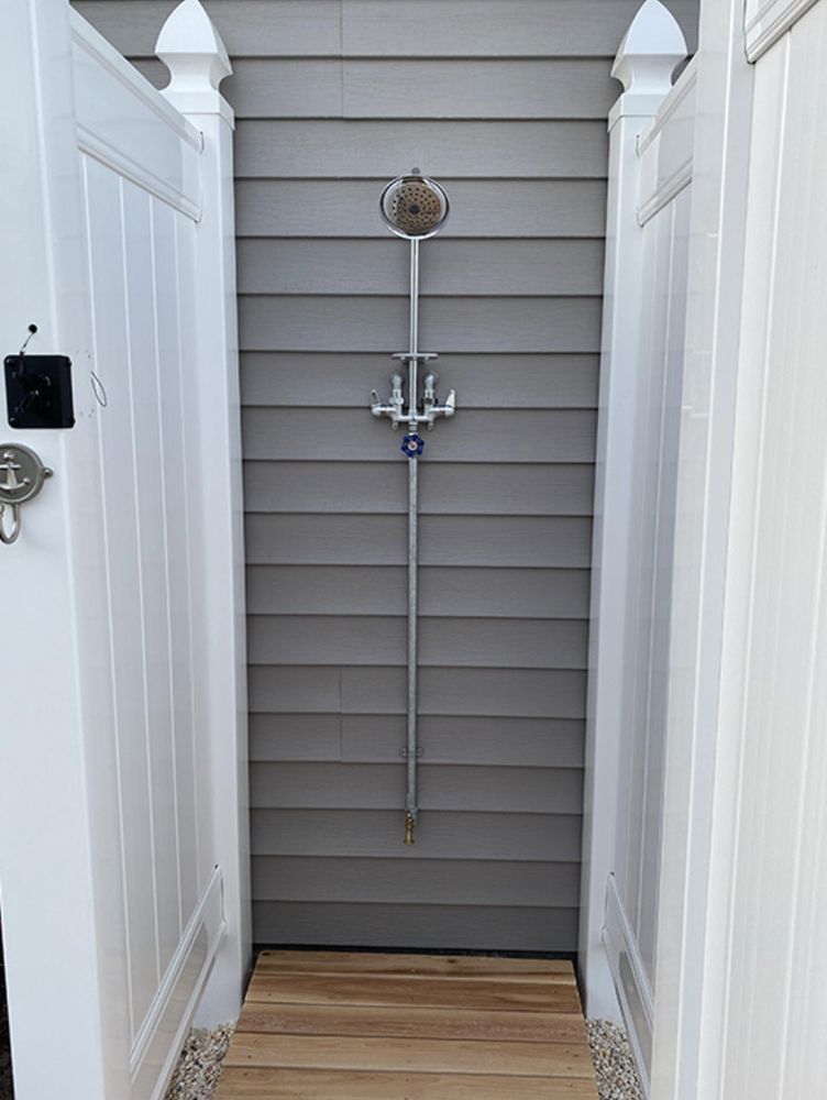 A white fence with a shower attached to it.