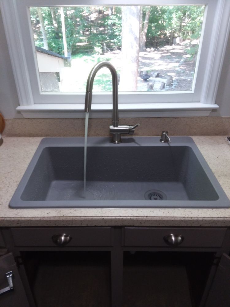 A kitchen sink with water running from the faucet