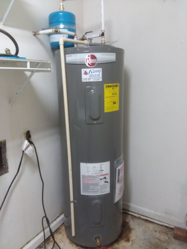 A gray water heater is sitting in a room next to a wall.
