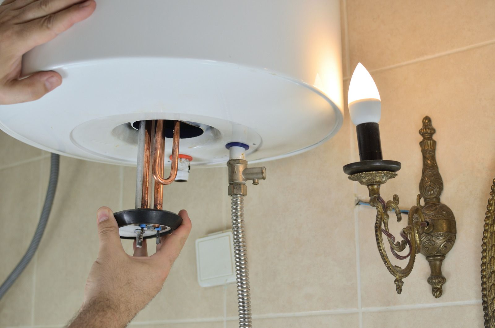 A person is fixing a water heater in a bathroom.