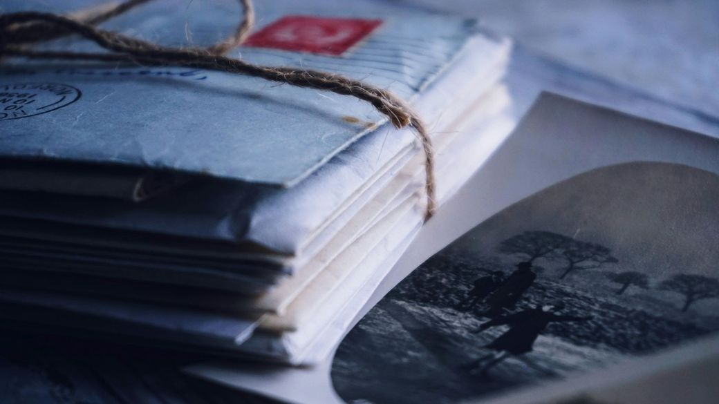 A stack of envelopes tied with string next to a picture of a man riding a horse.