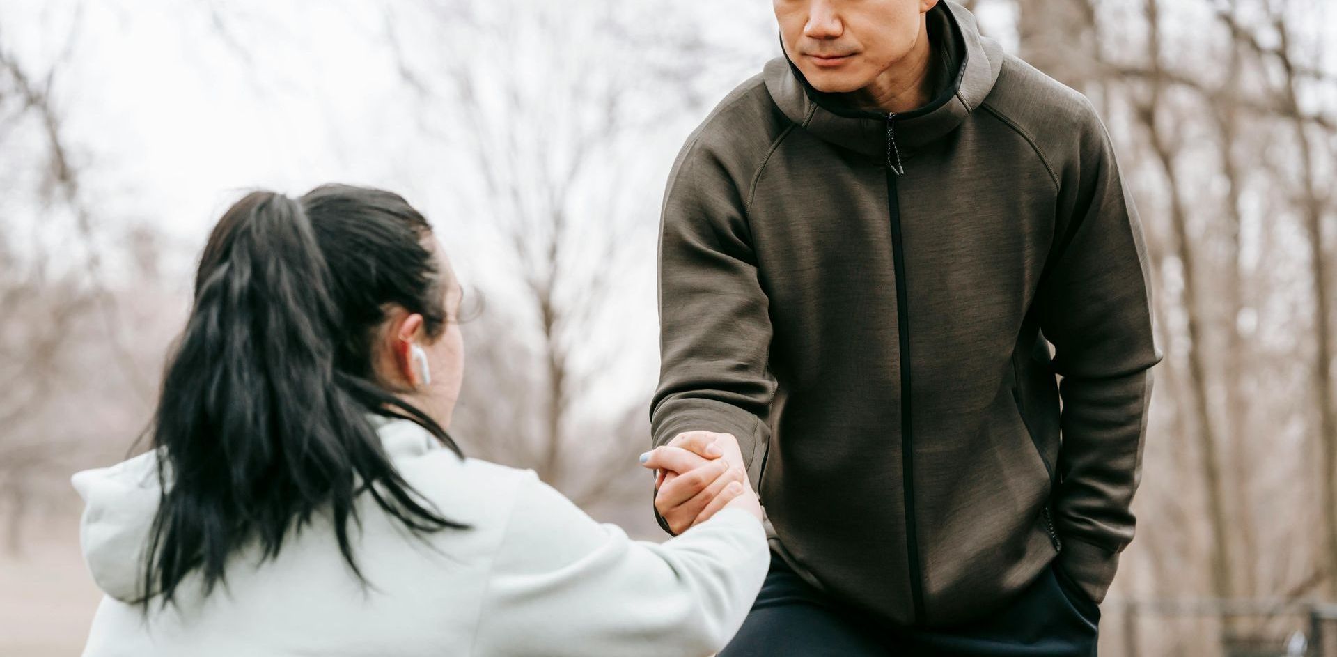 A man and a woman are shaking hands in a park.