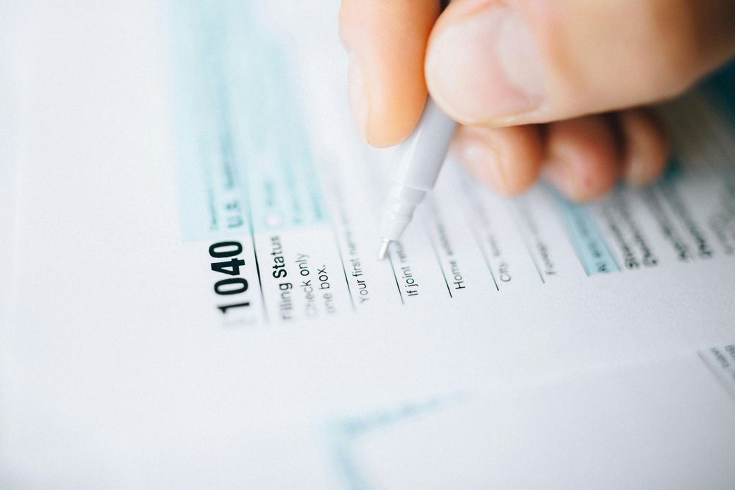 A person is filling out a tax form with a pen.