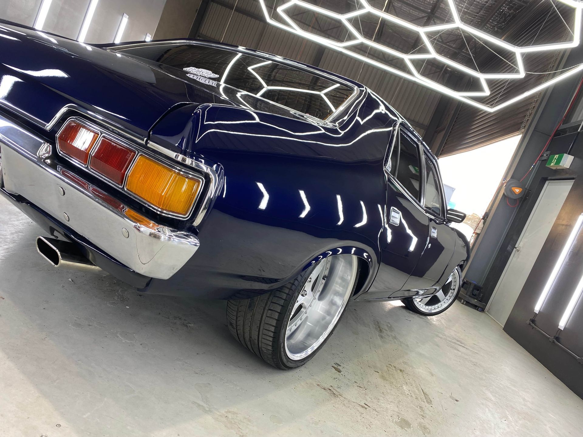 A Man Is Polishing The Headlights Of A Black Car — The Works Auto Salon In East Bendigo, VIC
