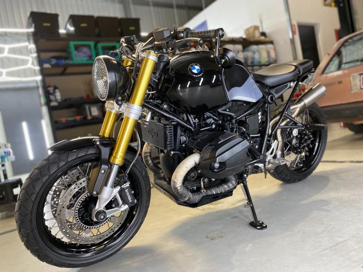 A Black Motorcycle Is Parked In A Garage Next To A Car — The Works Auto Salon In East Bendigo, VIC