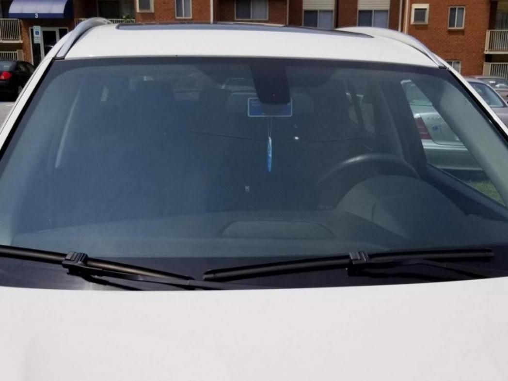 A white car is parked in front of a brick building