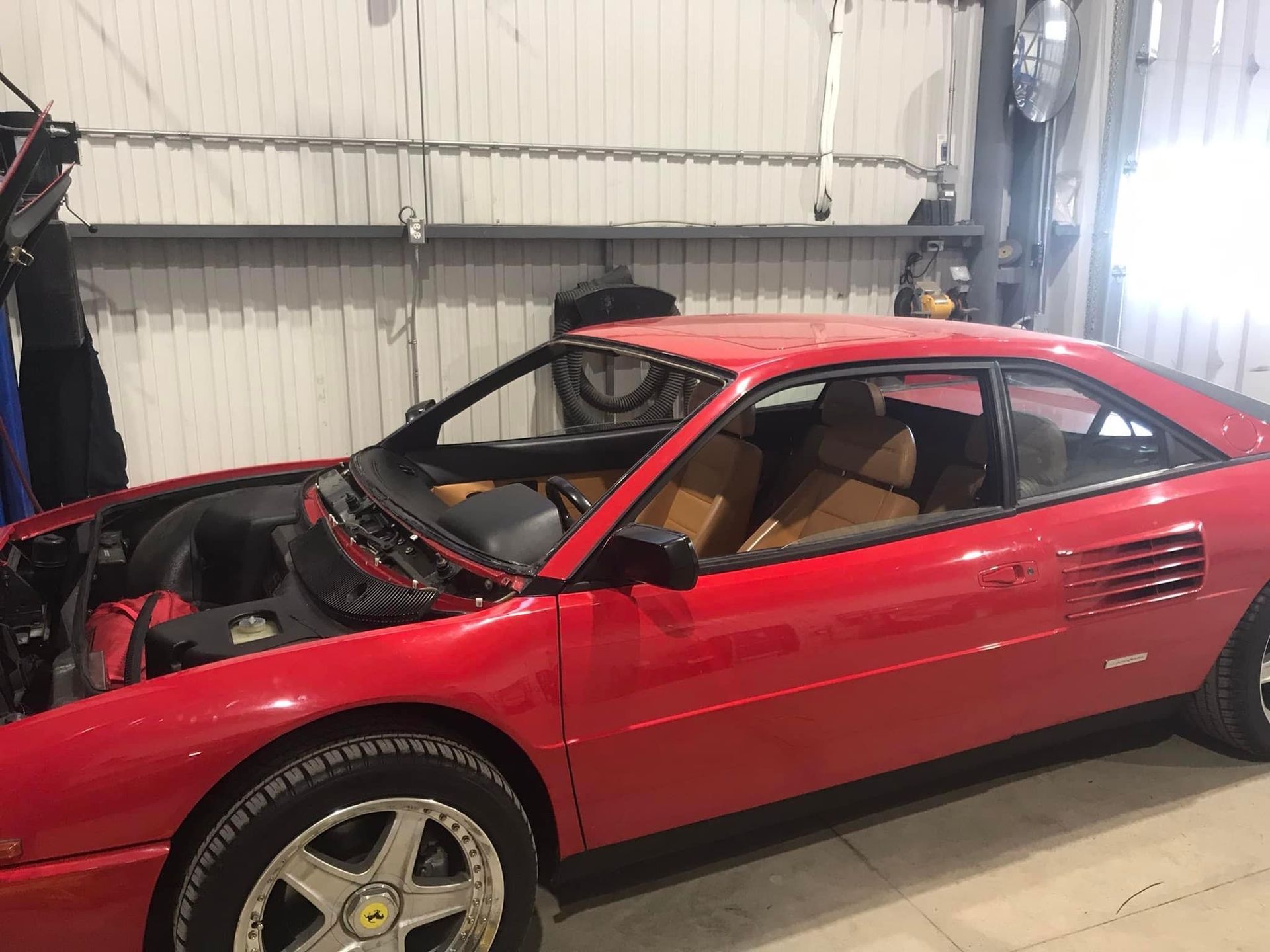 Une Ferrari rouge est garée dans un garage avec son capot ouvert.
