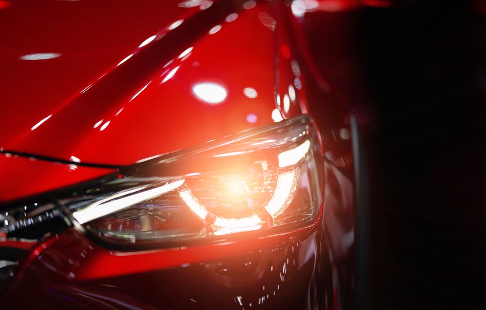 Un gros plan du phare d'une voiture rouge dans une pièce sombre.