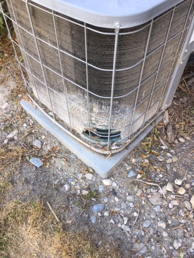 A close up of a dirty air conditioner on the ground.