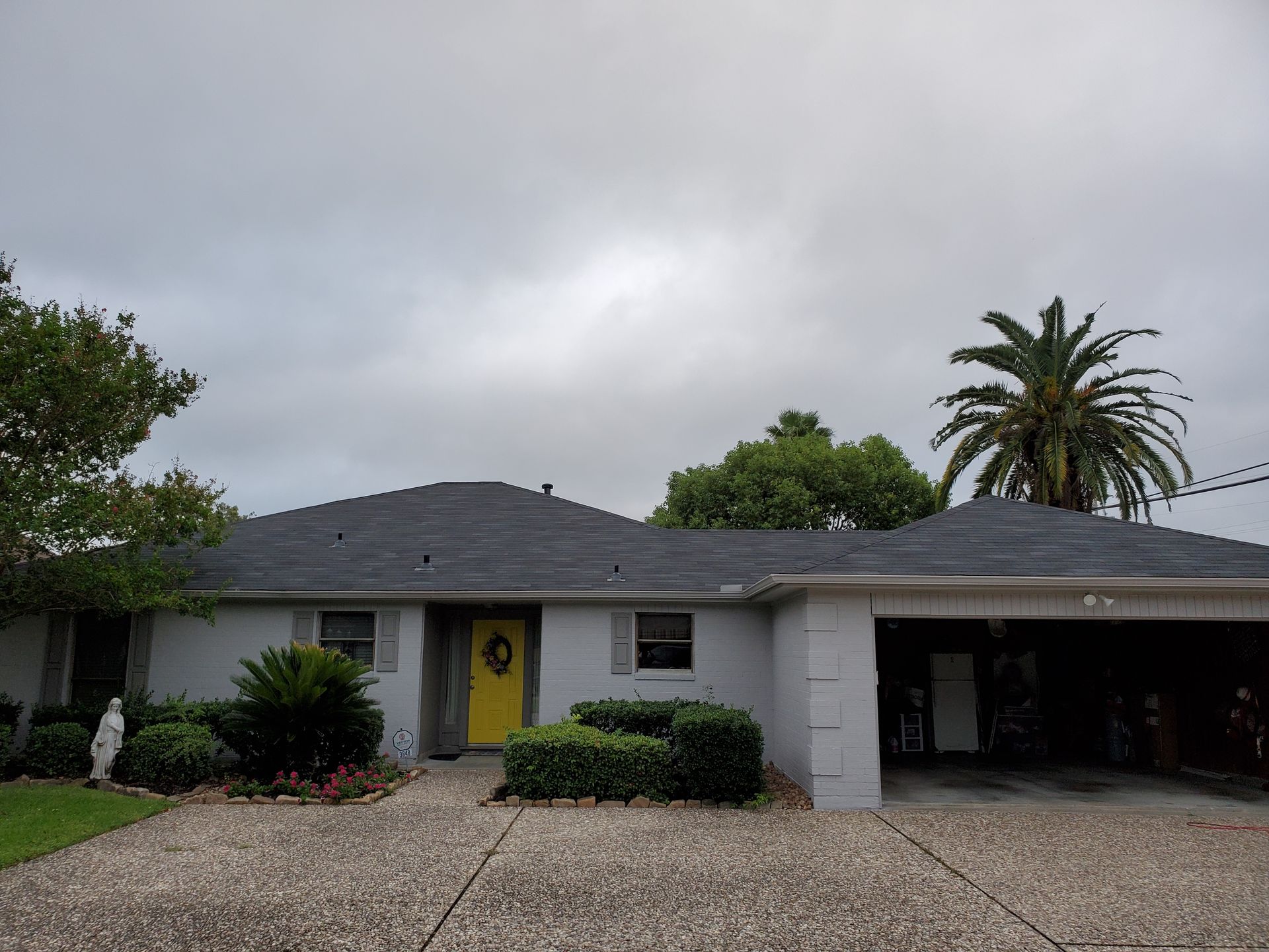 Person on ladder, working on house exterior with power tool.